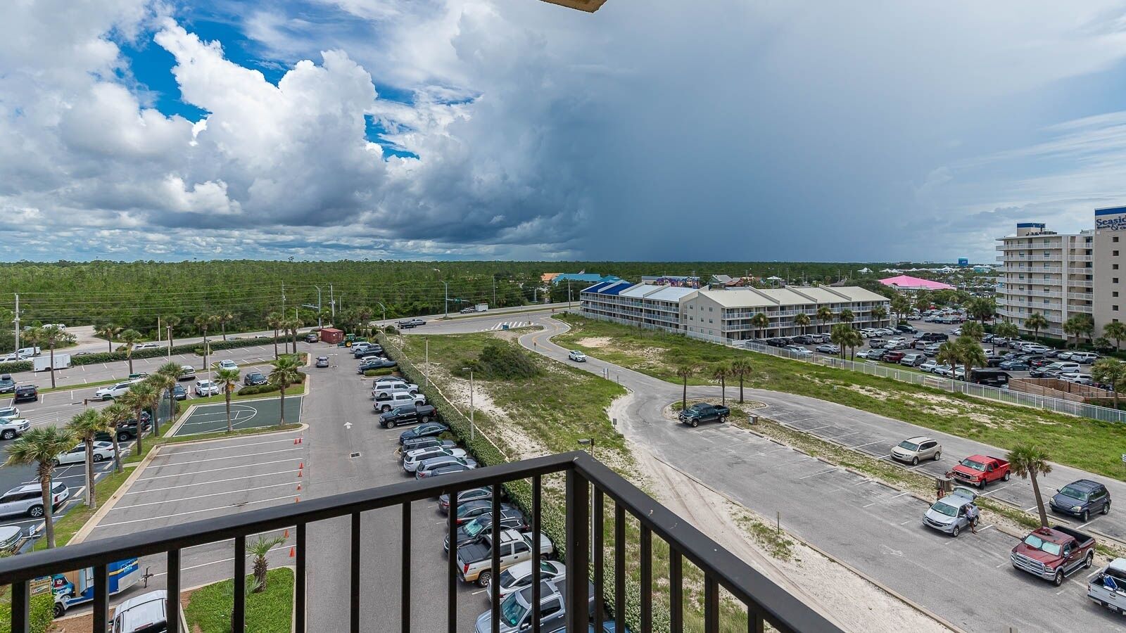 A hotel with a parking lot, a road with cars, and a building with a blue roof.