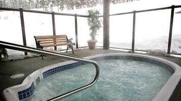 Ein Whirlpool mit Fliesenrand, eine Holzbank und ein Blumentopf.