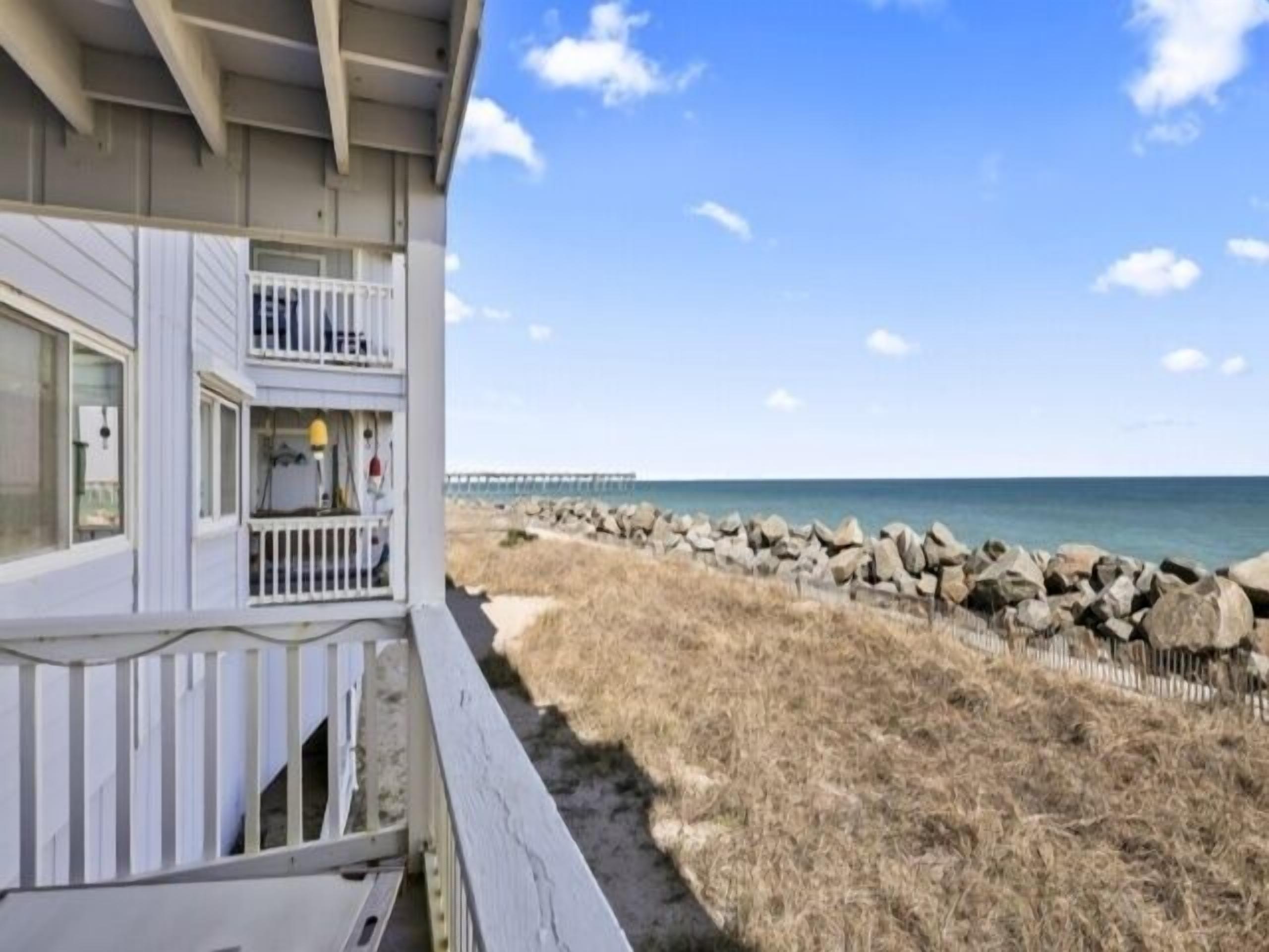 A beachfront property with a balcony overlooking the ocean.