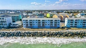 A coastal hotel with multiple floors, a rocky shoreline, and a view of the sea. - A Sea Escape 1 Bedroom Villa (Carolina Beach)