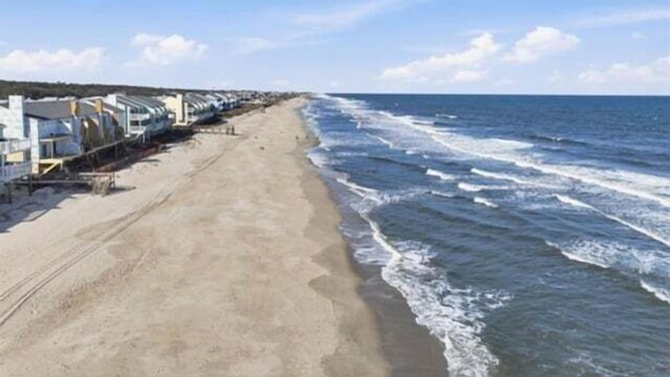 Ein Strand mit einer Reihe weißer Gebäude entlang der Küste.