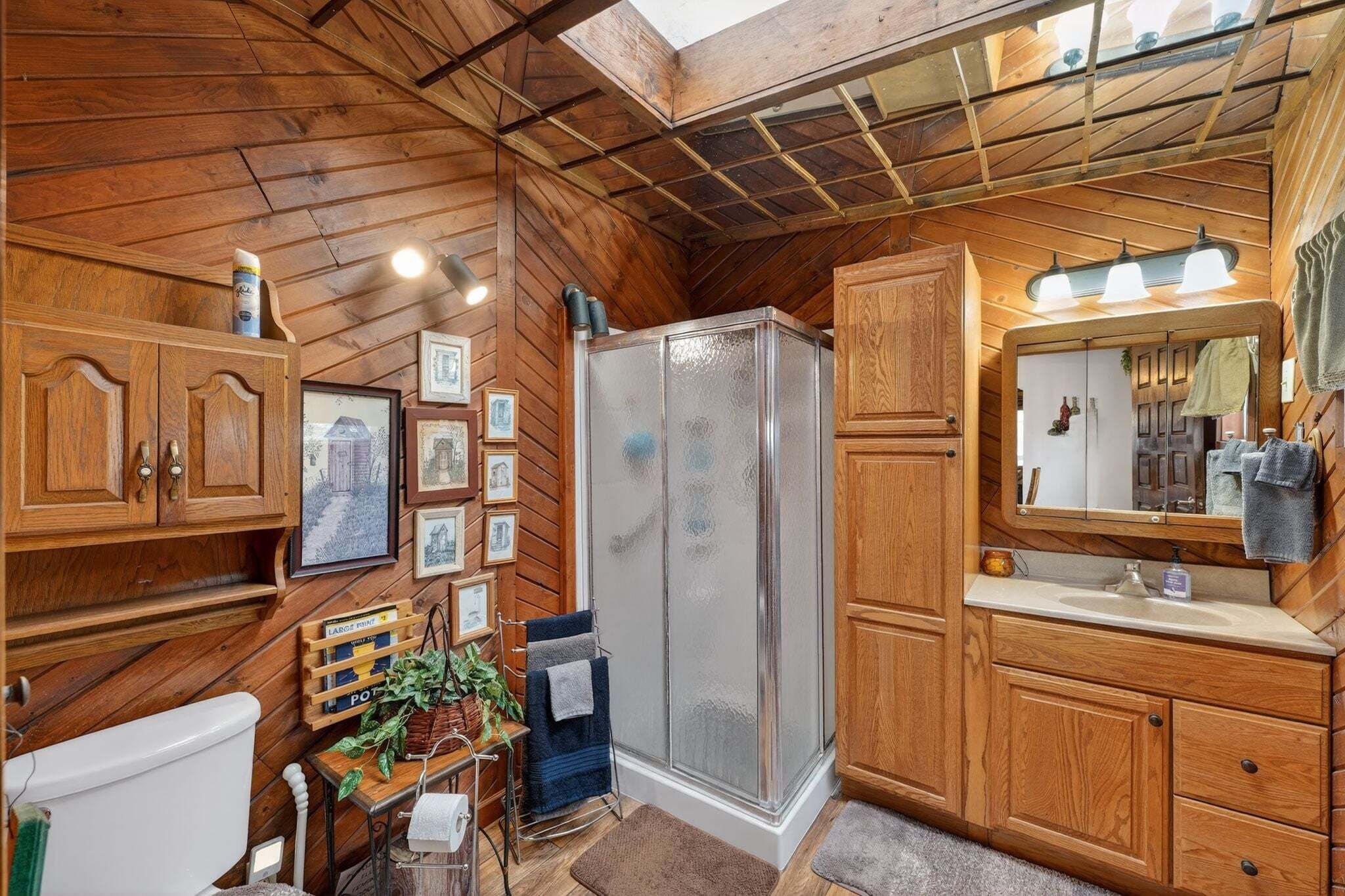 A wooden bathroom with a shower, toilet, and vanity.