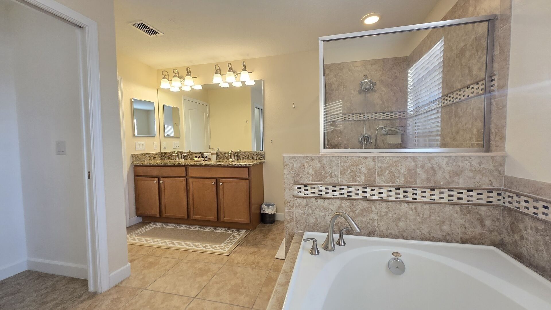 A modern bathroom with a freestanding bathtub, a vanity with a granite countertop, and a large mirror above the sink.