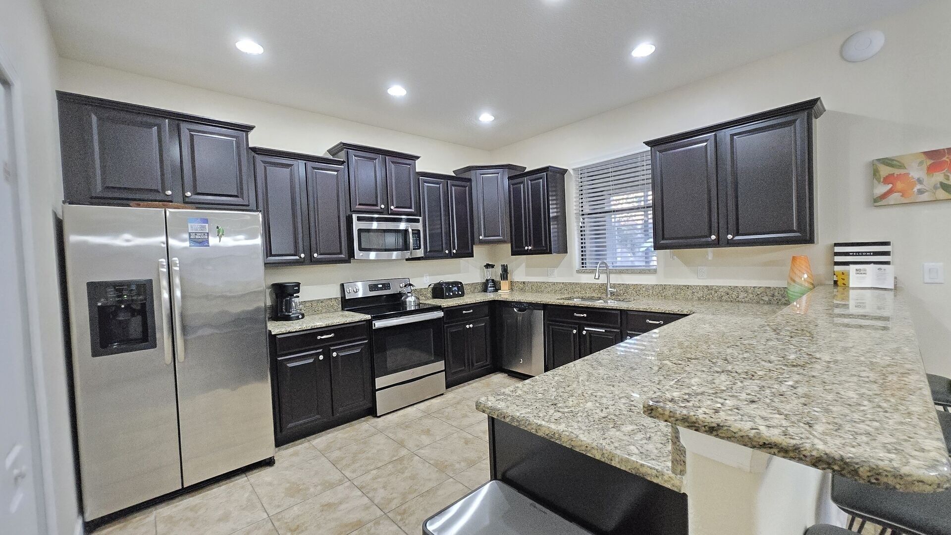 A modern kitchen with dark cabinets, stainless steel appliances, and a granite countertop.