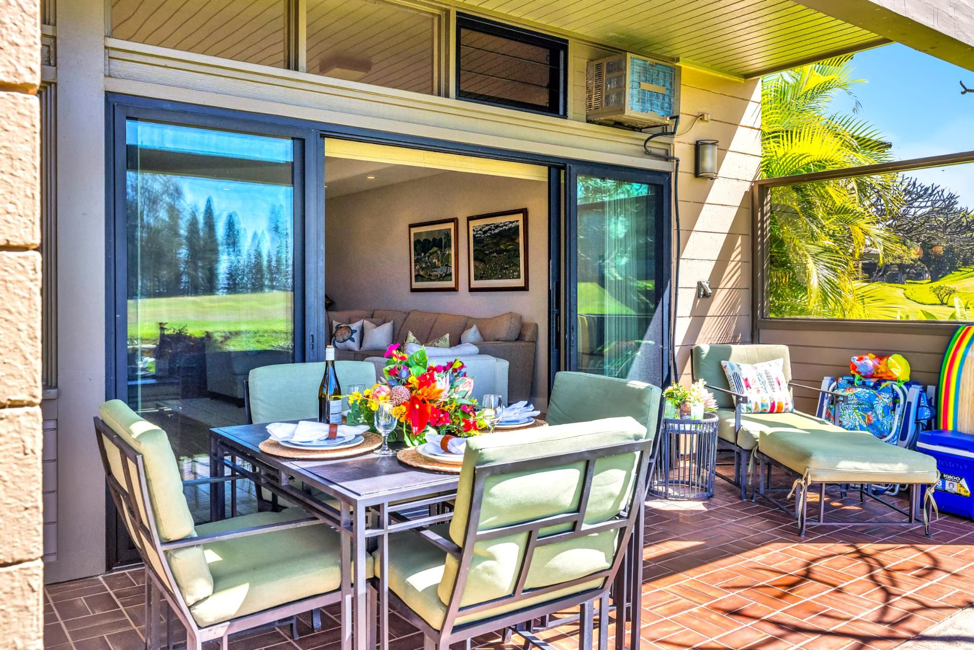A dining area with a table set for two, a sofa, and a view of a garden.