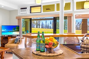 Eine Bar mit Pellegrino-Flaschen, einer Obstschale und einem Fernseher, der eine Strandansicht zeigt.