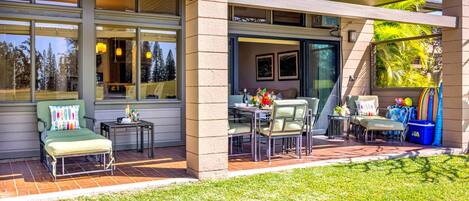 Un patio couvert avec coin salon extérieur, une table à manger et une vue sur le paysage environnant.
