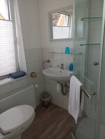Quarto solteiro básico | Banheiro | Chuveiro, toalhas de banho, papel higiênico 