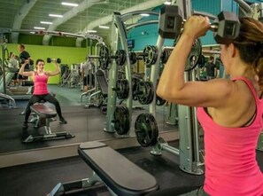 Ein Fitnessstudio mit verschiedenen Trainingsgeräten, darunter Kurzhanteln und Kraftgeräte.