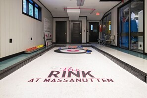 Eine Halle mit einer Curlingbahn in Massanutten, mit einem polierten Boden, Curlingsteinen und einer Zielscheibe.