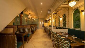 A restaurant with a long counter, booths, and patterned chairs.