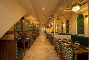 Un restaurant avec un long comptoir, des banquettes et des chaises à motifs.