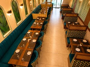 Un restaurante con mesas largas compartidas y cabinas, dispuestas en fila.