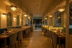 A restaurant with a long dining area, multiple tables, and chairs. - Andies Hotel (Kharar)