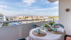 Een balkon met een tafel gedekt voor twee, met uitzicht op een jachthaven en gebouwen in de verte.