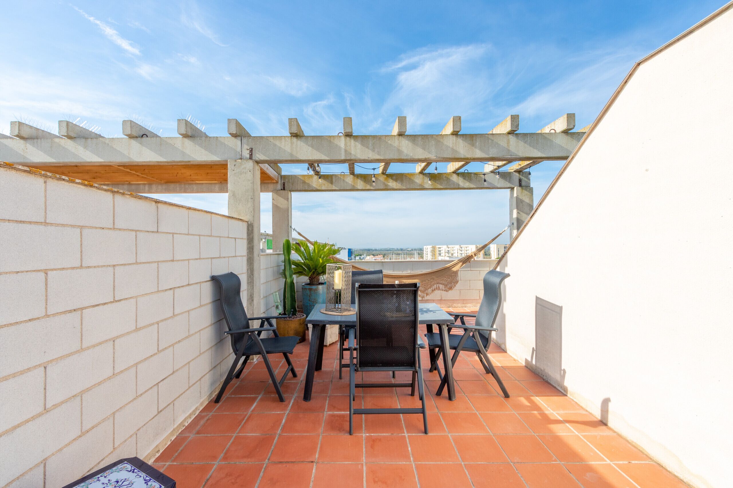 A terrace with a pergola, tiled floor, and outdoor furniture.