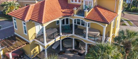 A multi-story house with a red-tiled roof, a balcony, and a well-maintained garden.