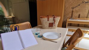 A dining table with a notebook, glasses, a plate, and a wicker basket. - Banyuls-sur-Mer: Sea View Apartment, Terrace, Private Parking, 4 People (Banyuls-sur-Mer)