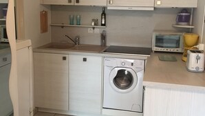 A compact kitchen with a washing machine, a toaster, and a microwave. - Ground Floor with Private Parking for 4 (Argelès-sur-Mer)