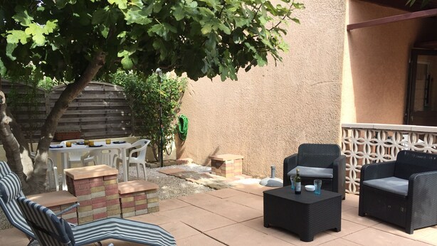 An outdoor patio with striped lounge chairs, a black coffee table, and a wicker sofa. - Ground Floor with Private Parking for 4 (Argelès-sur-Mer)