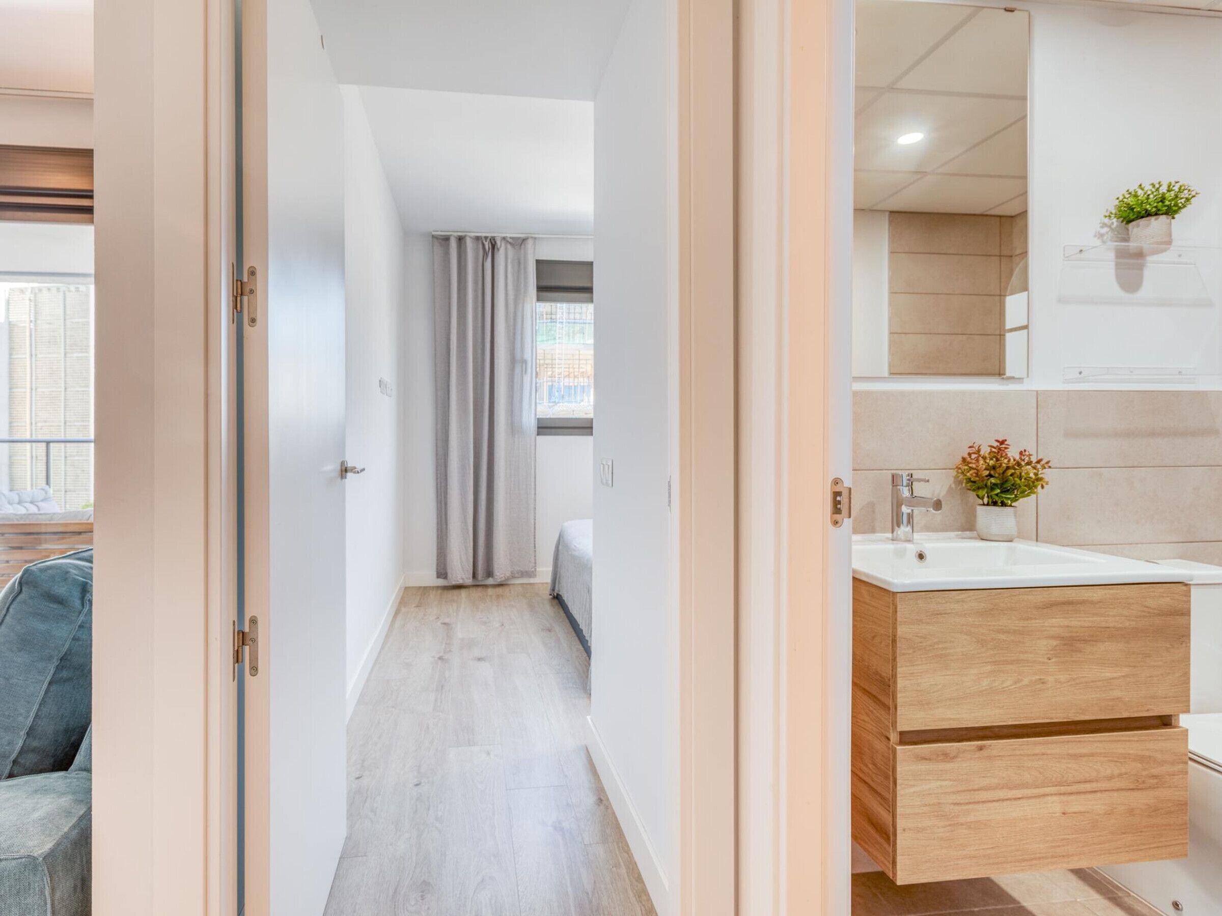 A modern bathroom with a wooden vanity, a sink, and a mirror.