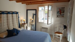 Een slaapkamer met een bed, een stoel, een bureau, een spiegel en een raam.