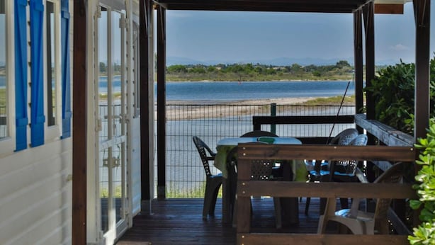 Une terrasse en bois avec une table et des chaises donnant sur une plage.