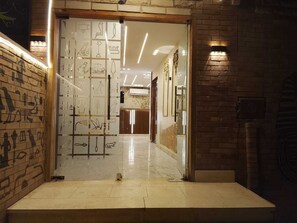 Eine Hotelhalle mit modernem Design, inklusive einer Glastrennwand mit ägyptischen Hieroglyphen, einem polierten Marmorboden und einer Ziegelwand rechts.