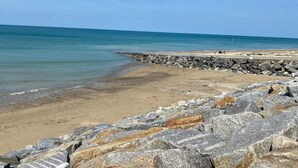 Une plage avec une digue rocheuse et une mer calme.