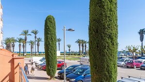 A parking lot with cars, a pedestrian walkway, and tall, neatly trimmed hedges. - 0088-MIRABLAU Apartment with side views of the beach (Empuriabrava)