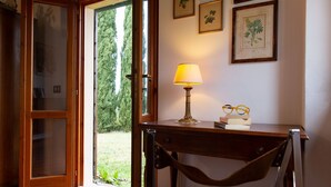 Une pièce avec un bureau en bois, une lampe et une porte donnant sur un jardin.