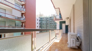 En gang med flisegulv, en balkon med gelænder, og en bygning med flere etager og balkoner.