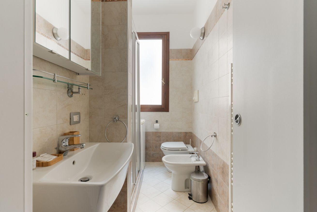 A modern bathroom with a bathtub, toilet, bidet, and a glass shower enclosure.