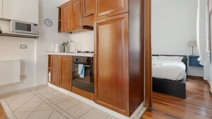 Una cocina pequeña con gabinetes de madera, un microondas y una estufa.