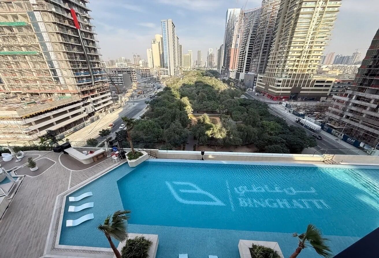 A rooftop pool with a clear view of the cityscape, surrounded by high-rise buildings and greenery.