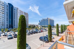 Ein Parkplatz mit mehreren Autos, hohen Gebäuden und blauem Himmel.