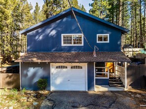 Ein zweistöckiges Haus mit Garage, überdachter Veranda und kleinem Vorgarten.