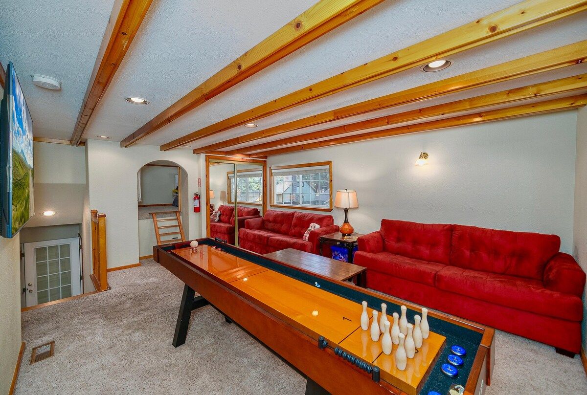 A room with a pool table, red sofas, and wooden beams on the ceiling.