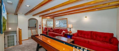 A room with a pool table, red sofas, and wooden beams on the ceiling.