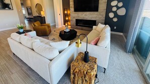 Un salon moderne avec un grand canapé, une table basse et une cheminée.