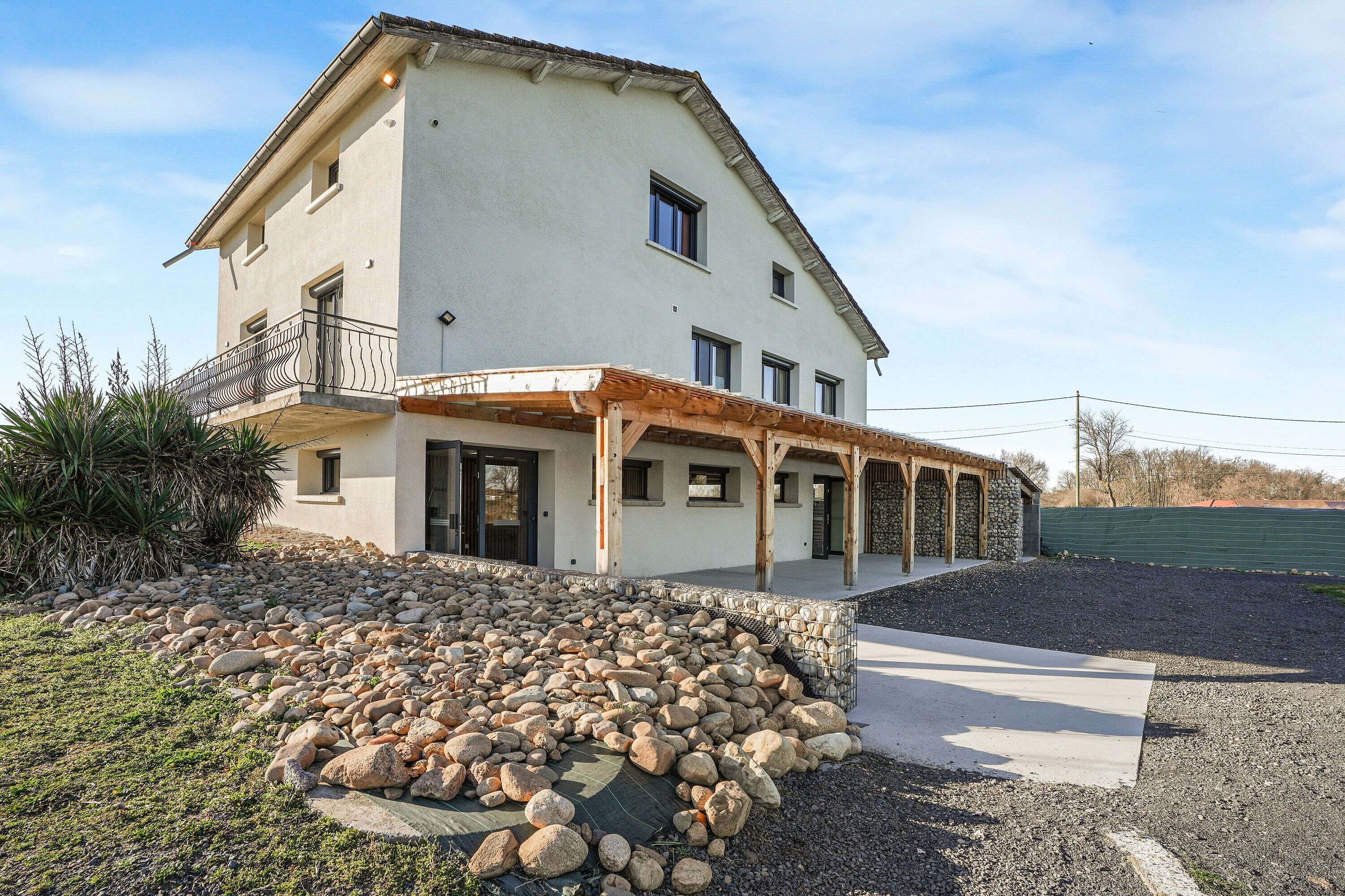 Una casa a due piani con un balcone, un vialetto in pietra e un piccolo giardino.
