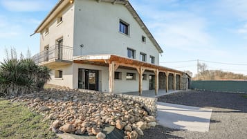 Una casa a due piani con un balcone, un vialetto in pietra e un piccolo giardino.