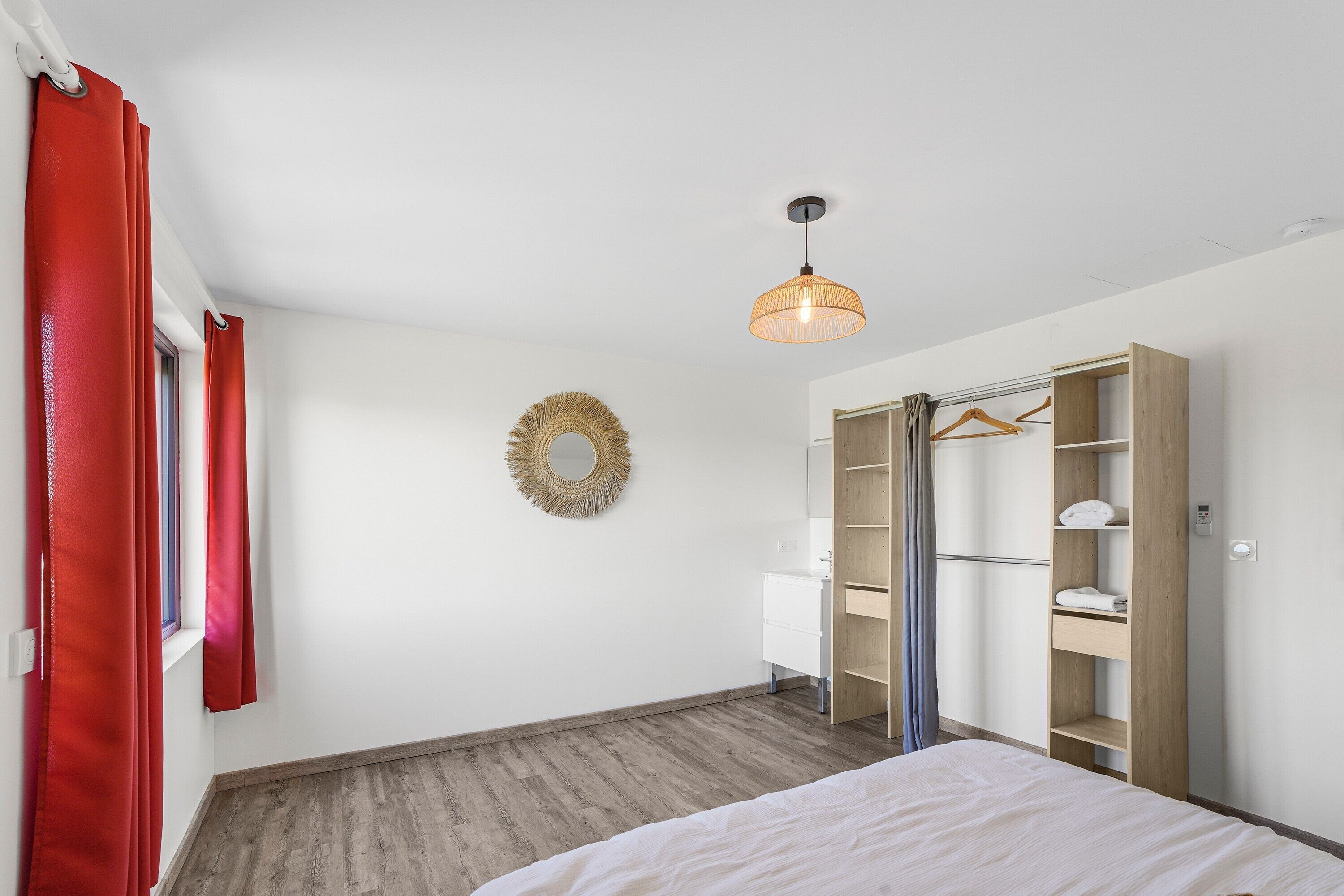 Una camera da letto con un letto, un armadio, uno specchio e una lampada a sospensione.