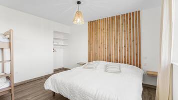 Une chambre avec un lit, un mur revêtu de lambris en bois, un luminaire suspendu et une échelle en bois.
