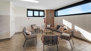 Ein Zimmer mit Korbmöbeln, einem Feuerlöscher und großen Fenstern.