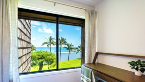 Una habitación con un ventanal grande que ofrece vistas a palmeras y al océano.