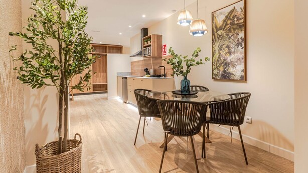 Una cocina moderna con armarios de madera, una mesa de comedor con sillas y una lámpara colgante.