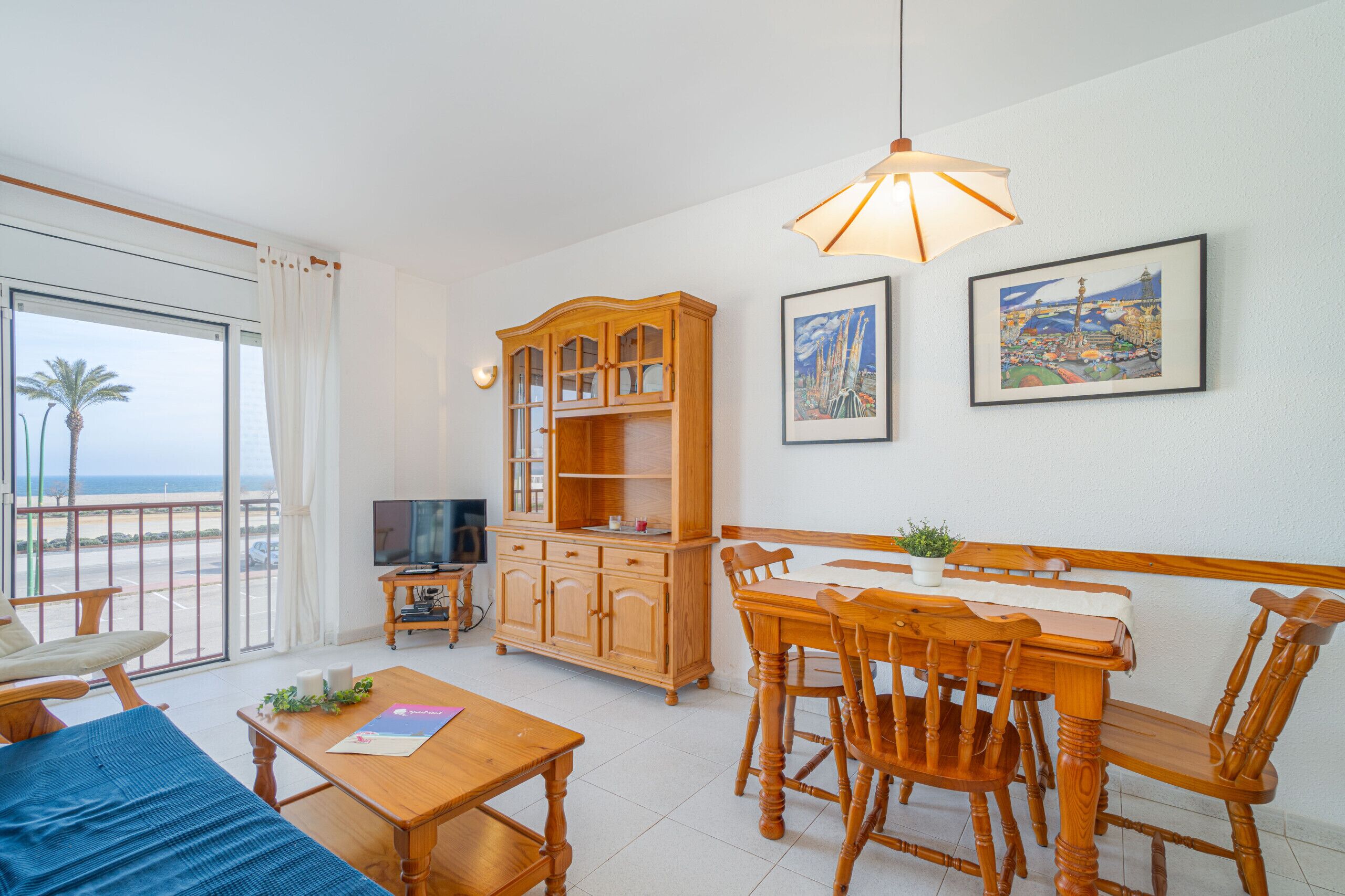 A spacious living room with a balcony, wooden furniture, a television, and artwork on the walls.