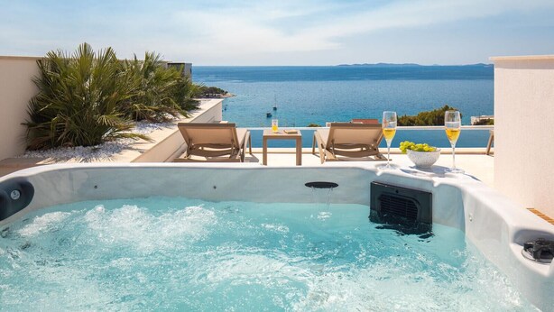 Een bubbelbad met twee loungesessels, een tafel met drankjes en uitzicht op zee.