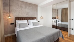 Een moderne slaapkamer met een groot bed, een spiegel en hanglampen.